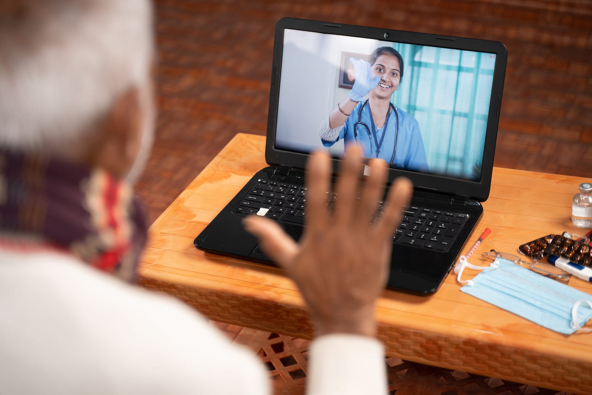 Shoulder shot of Old man on video with to doctor on laptop screen - concept of Online Chat, telehealth, or tele counseling with Nurse or Doctor during coronavirus or covid-19 pandemic