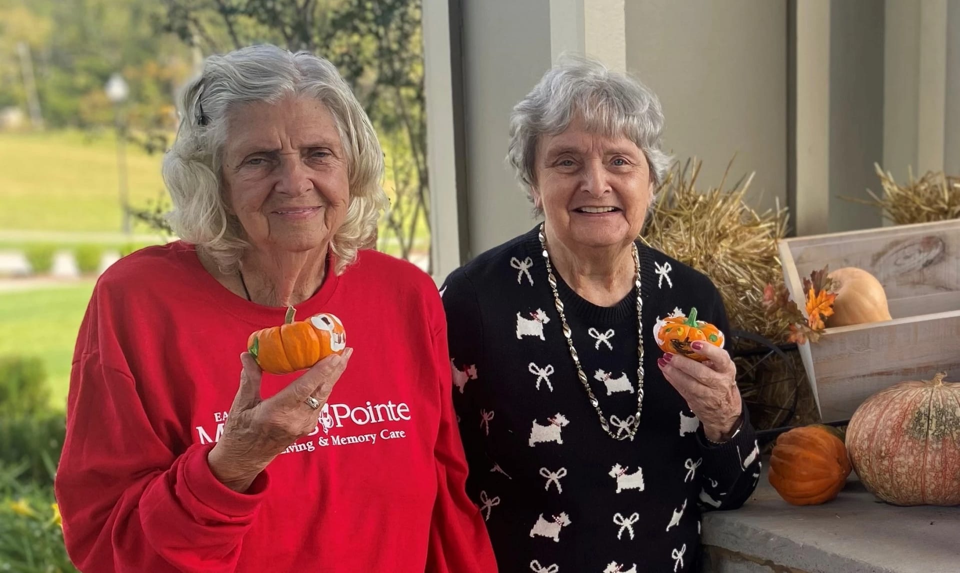 Two senior ladies posing with painted pumpkins