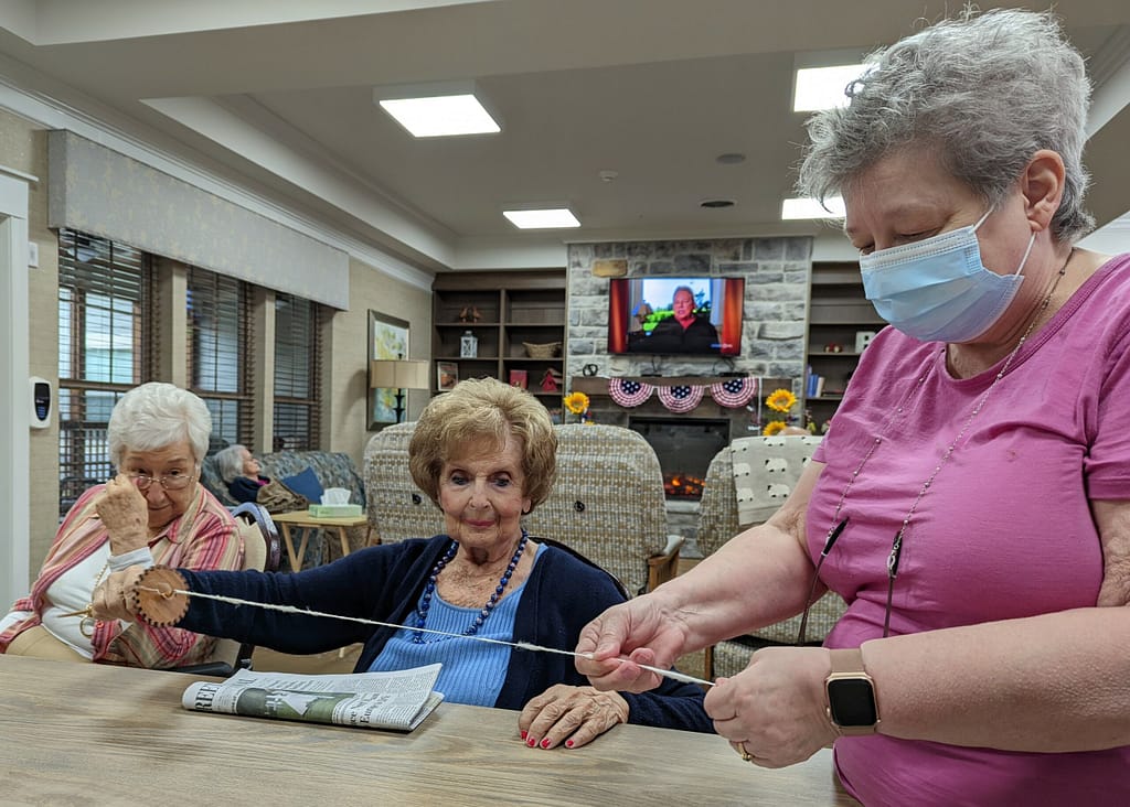 Photo of volunteer Pamela Kite showing how to spin thread from different materials at Morning Pointe of Hardin Valley in Knoxville, TN