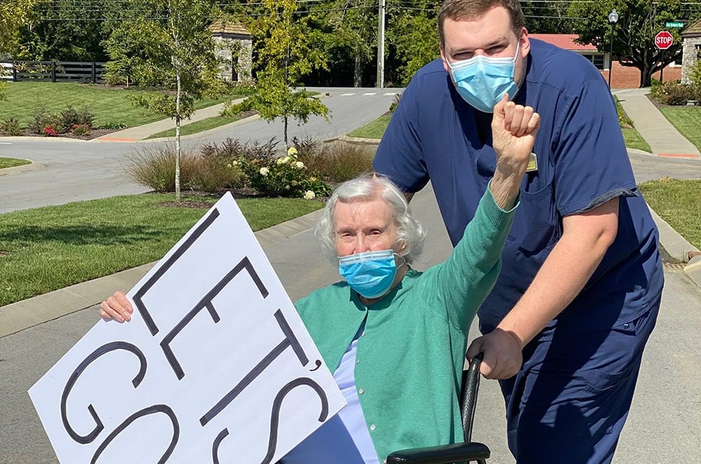 Senior lady cheering and holding a sign reading "Let's Go"