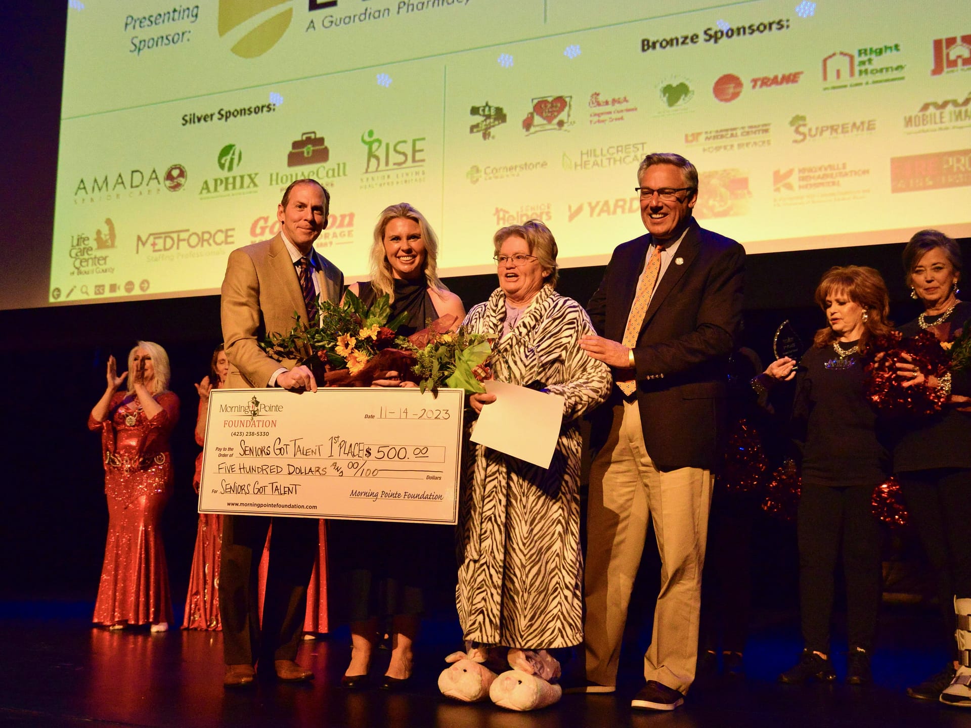 photo of the Morning Pointe Foundation's Seniors Got Talent - Knoxville show 2023 grand prize winner. Left to right: Franklin Farrow, Morning Pointe Senior Living Co-Founder and CEO; Miranda Perez, Morning Pointe Foundation Executive Director; Comedian Corkey Miller, winner; and Greg A. Vital, Morning Pointe Senior Living President