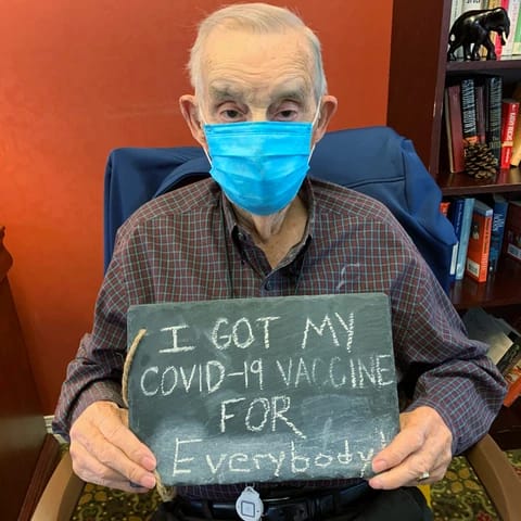 Senior man holding sign that reads "I got my COVID-19 vaccine for everybody"