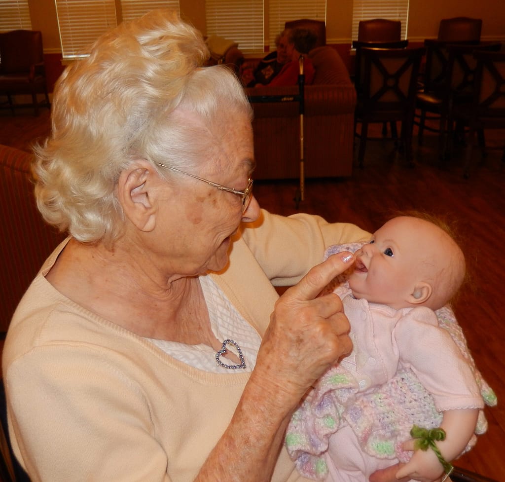 Resident Myra Walters holding a baby doll in cuddle therapy
