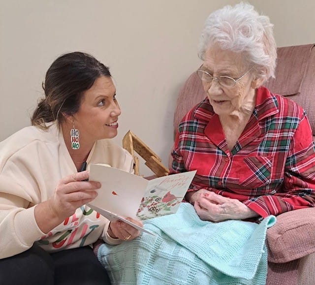 photo of Nicole Walton, life enrichment director, reading a Christmas card to June