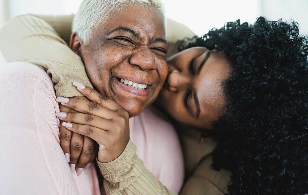 Daughter kissing elderly mother on the cheek at a senior living community