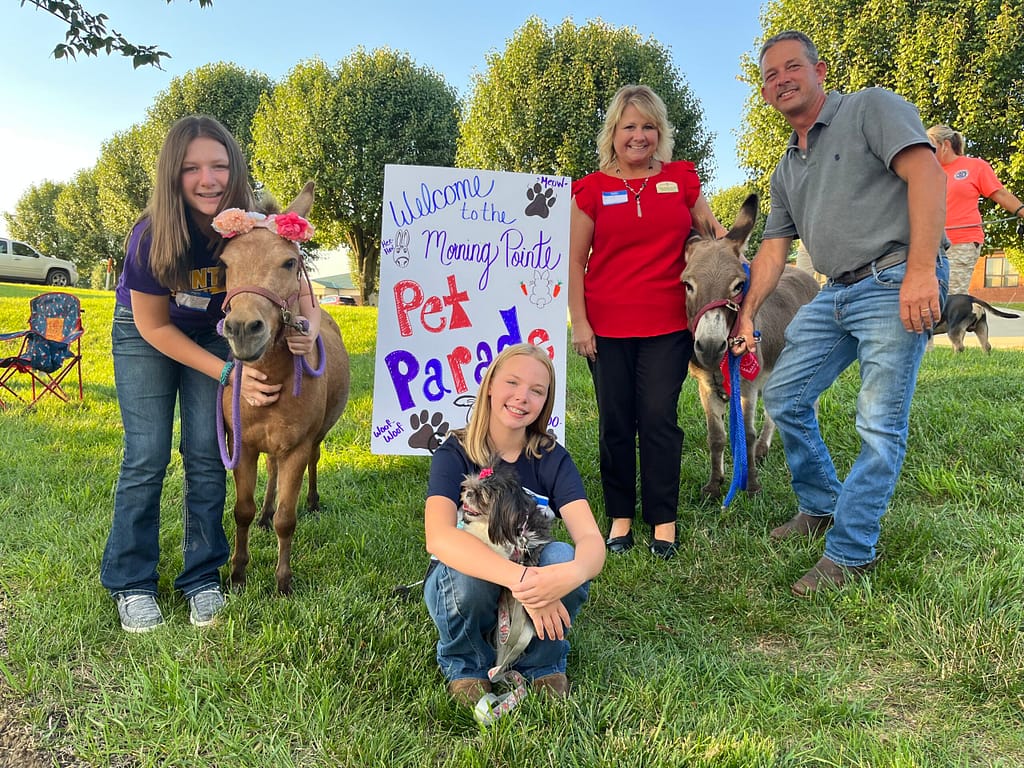 Photo of Natalie Winkler with mini donkey, Little Joe; Katie Moore with Shih Tzu, Macey; Cristy Winkler, Executive Director with her husband, JR Winkler, and their mini mule, Sugar Baby.