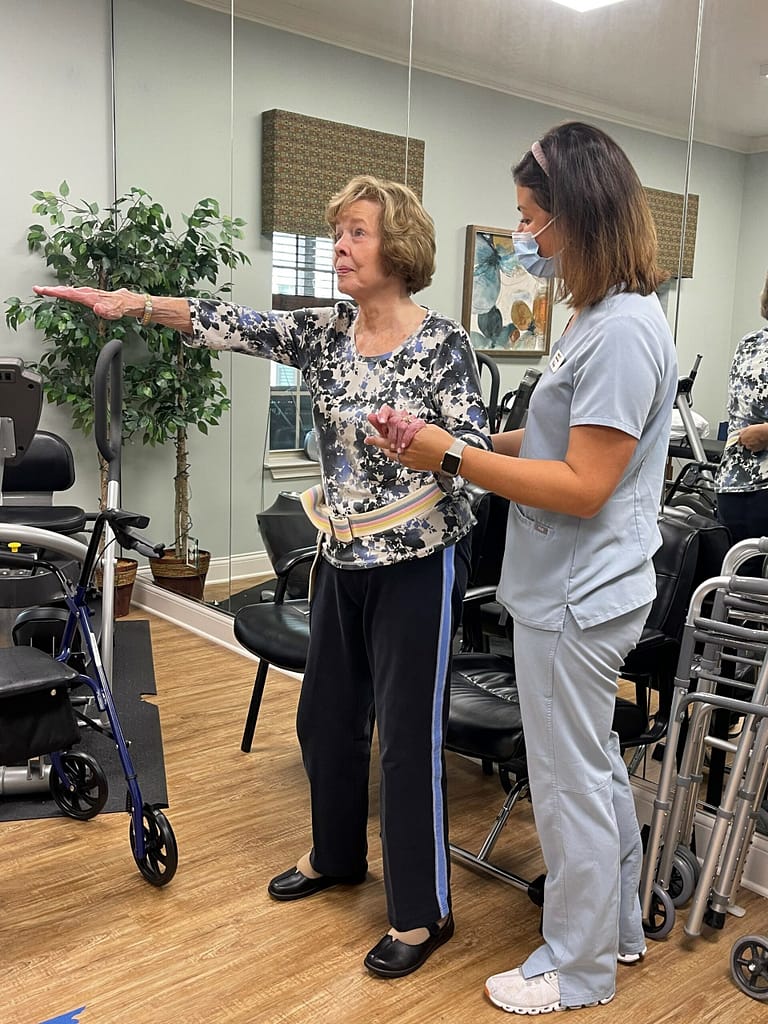 photo of therapist working with resident in therapy gym