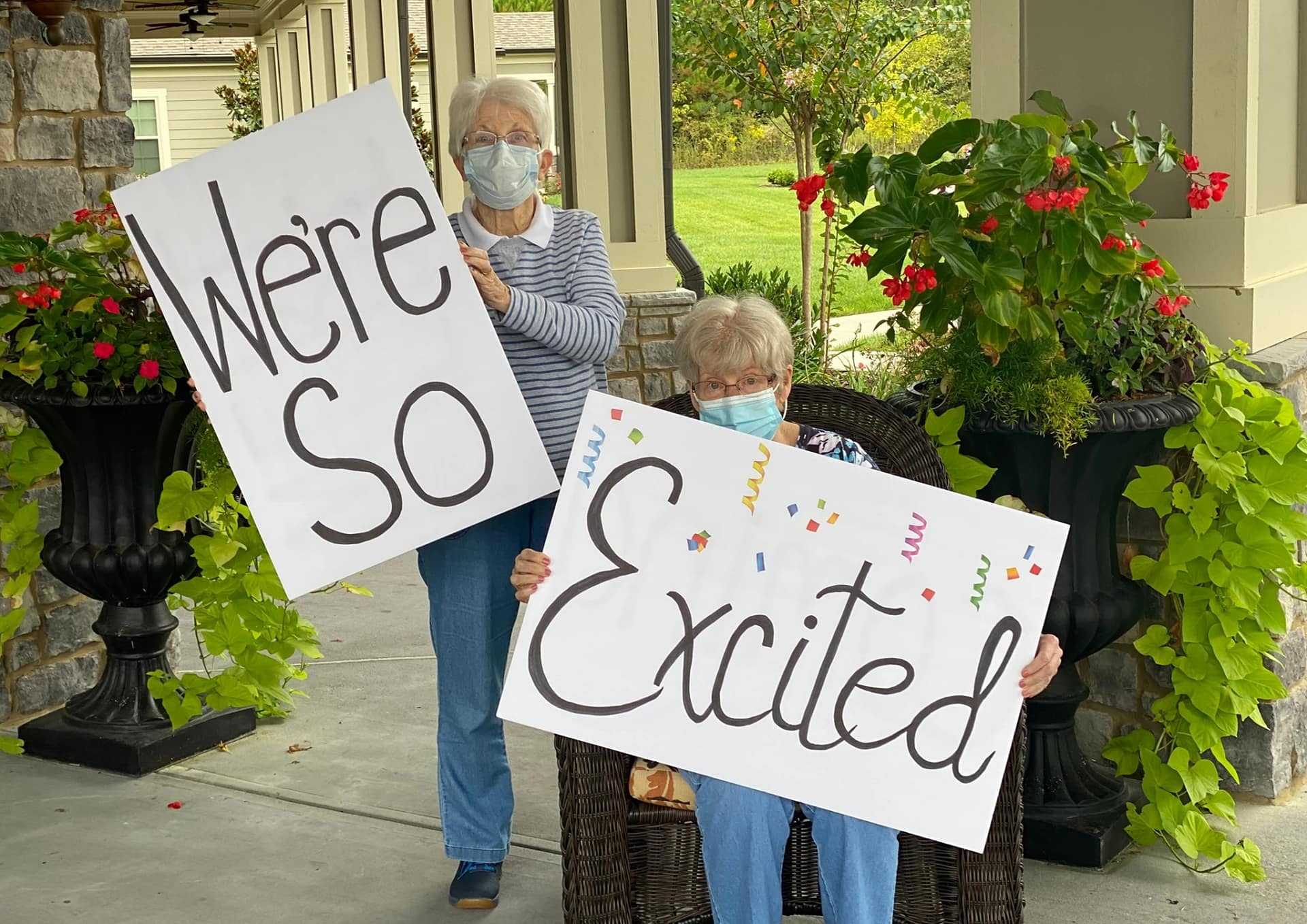 Two senior ladies holding signs that read "We're so Excited"