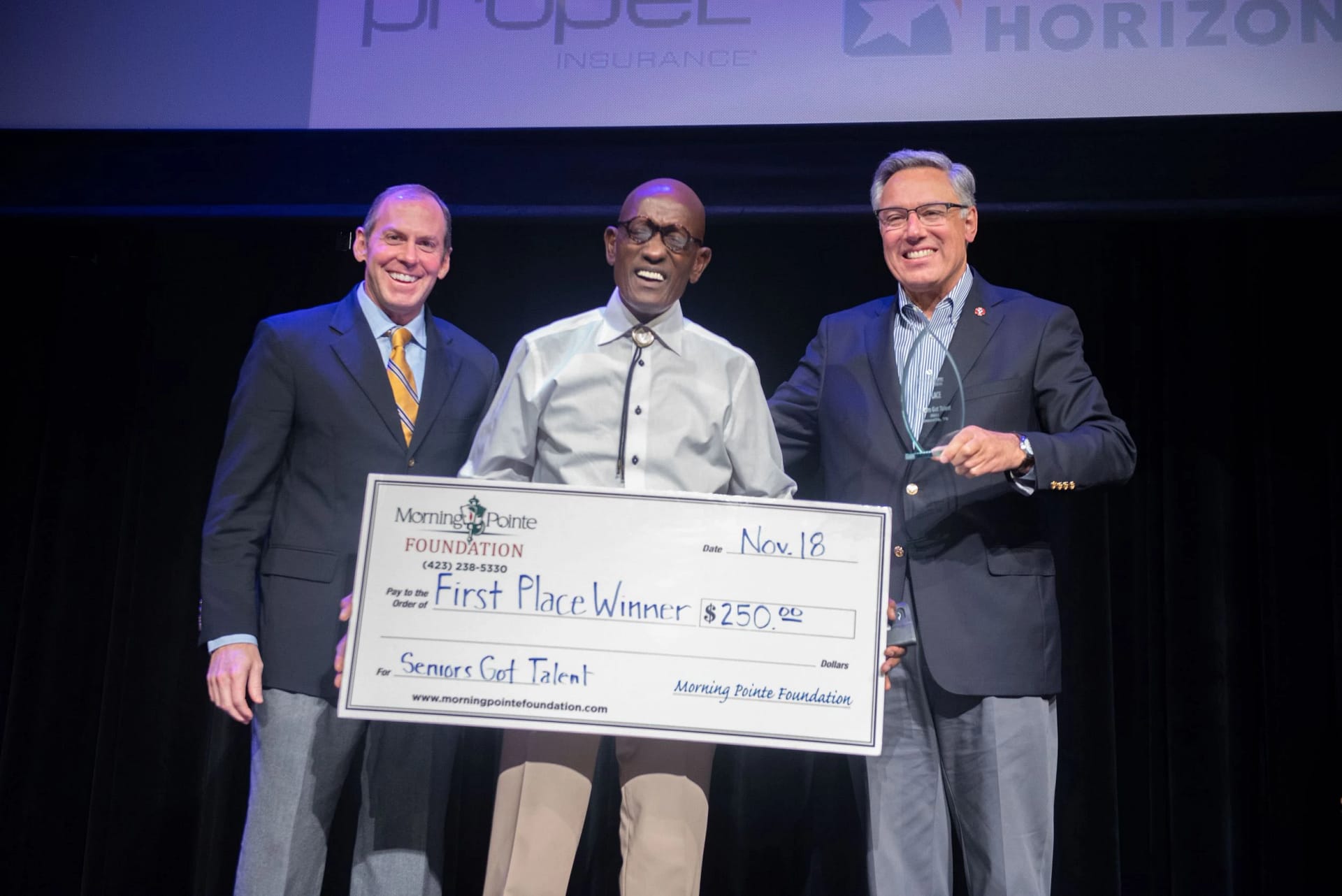 Seniors Got Talent winner holding a big cheque on stage