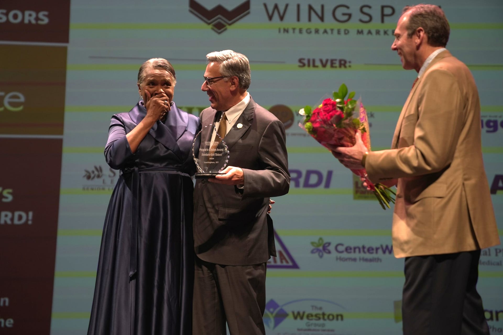 photo of Annette Dence receiving the People's Choice Award from Greg A. Vital, Morning Pointe Senior Living Co-Founder and President; and Franklin Farrow, Morning Pointe Senior Living Co-Founder and CEO