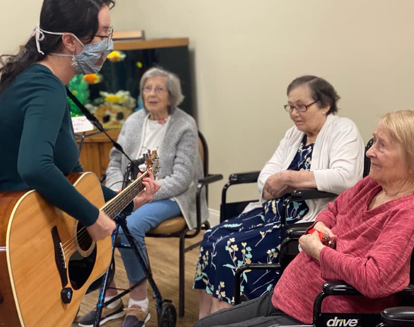 Volunteer playing a guitar for residents during music therapy