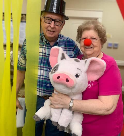 Dalton and his wife Barbara with a funny hat and red nose holding a stuffed pig