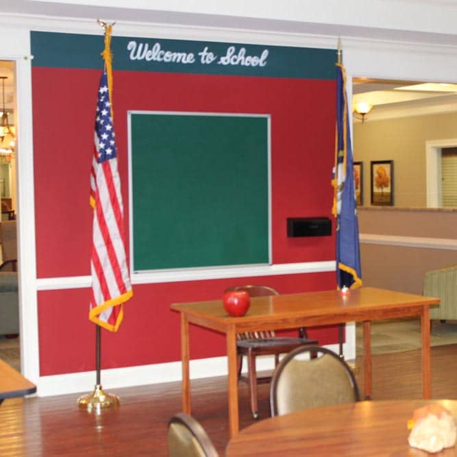 Classroom set up at Morning Pointe Senior Living with a teacher's desk and sign reading "welcome to school"