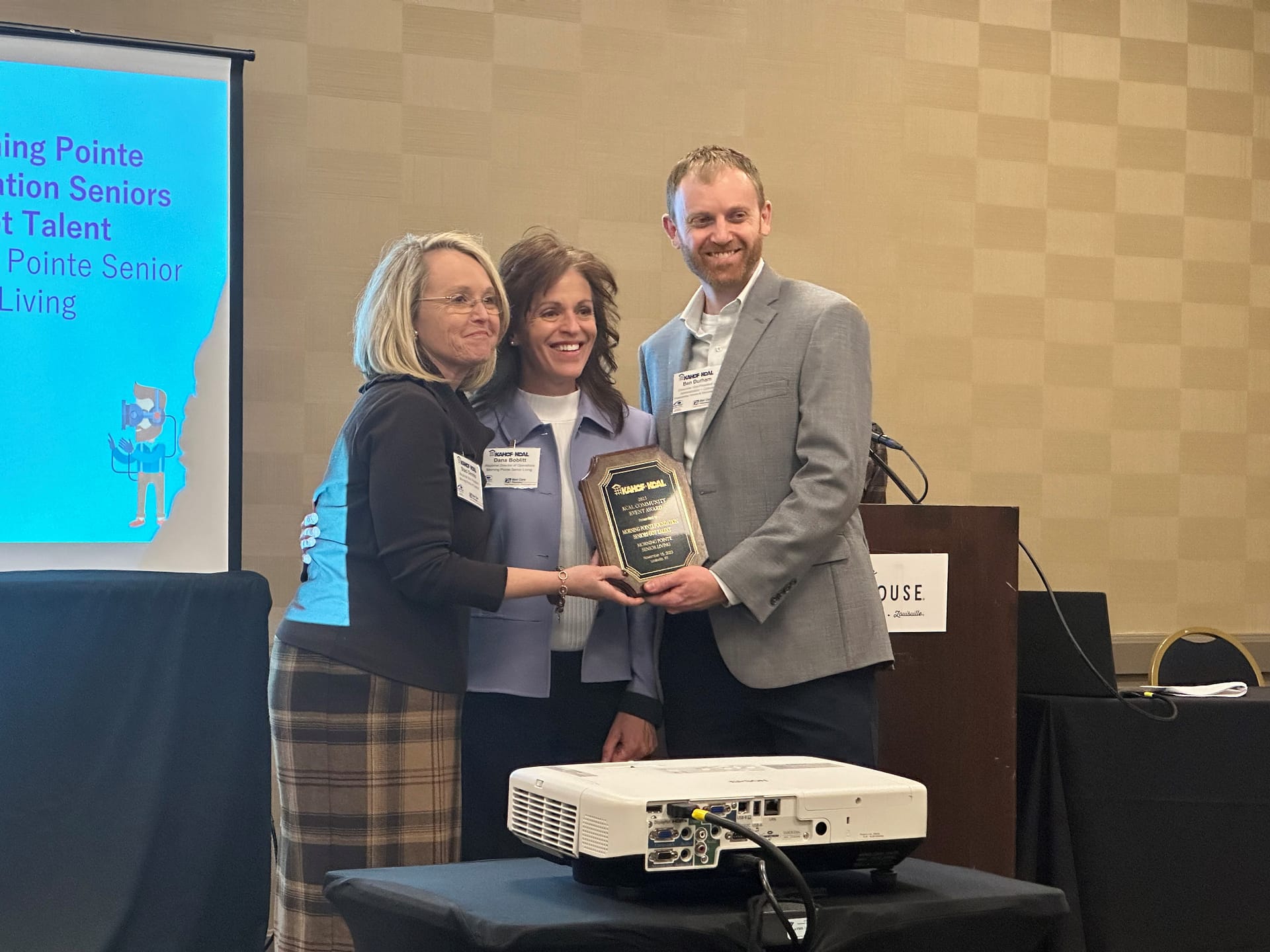 photo of Staci Dennis (left) and Dana Boblitt (center), Bluegrass Region Vice Presidents, receiving the Community Event Award for the Morning Pointe Foundation’s Seniors Got Talent – Lexington showcase from Ben Durham, Member of the KCAL Board of Directors