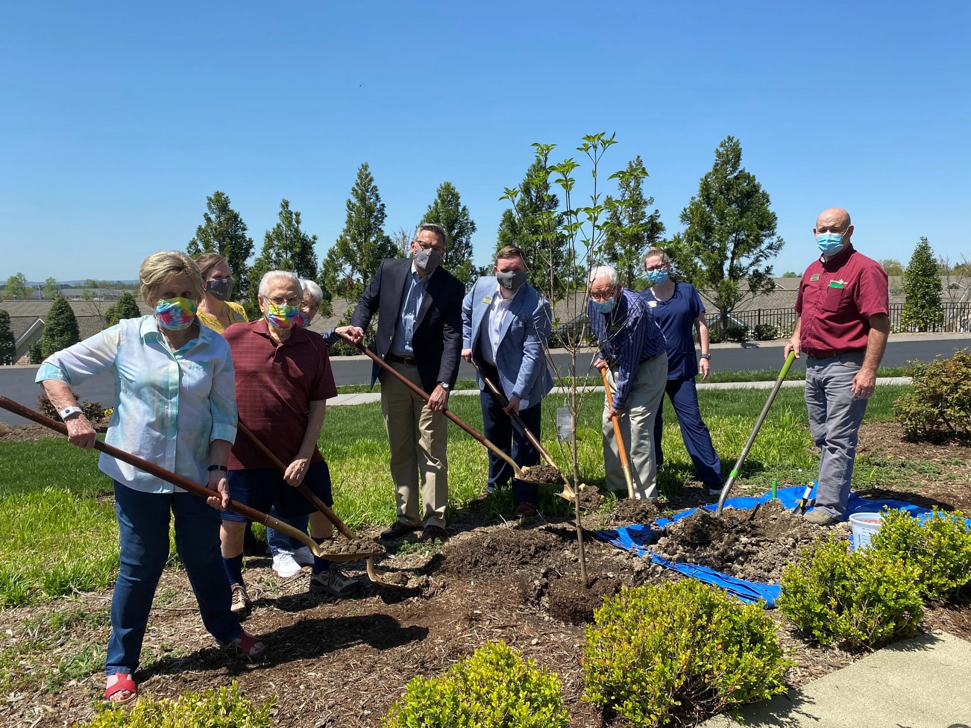 Group of residents and caregivers planting trees together