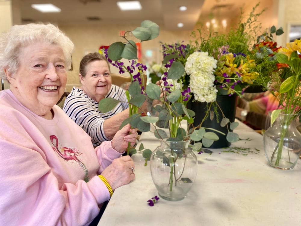 Two senior women at Morning Pointe Senior Living in Greenbriar Cove, Tennessee, rearranging flower bouquets together