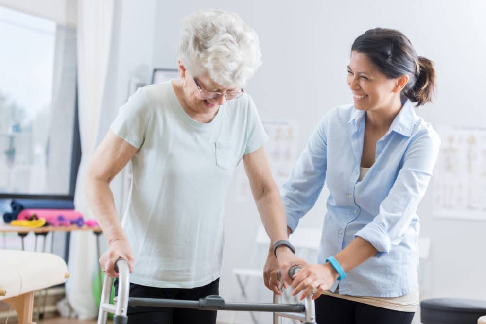 Medical caregiver for senior woman assisting with walker