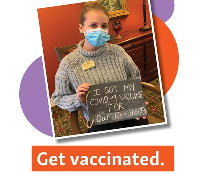 Employee holding sign that reads "I got my COVID-19 vaccine for our residents"